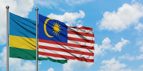 Rwanda and Malaysia flag waving in the wind against white cloudy blue sky together. Diplomacy...