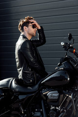 handsome young man sitting on motorcycle and readjusting hair