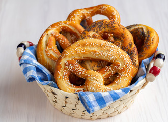 Homemade soft bavarian pretzel with salt, poppy and sesame seeds in a basket. Wooden background. Selective focus.