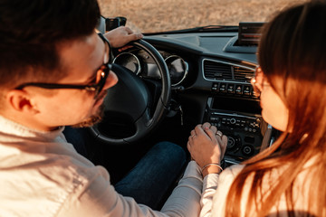 Young Happy Couple Dressed Alike in White Shirt and Jeans Enjoying Road Trip at Their New Car, Beautiful Sunset on the Field, Vacation and Travel Concept
