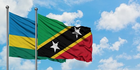 Rwanda and Saint Kitts And Nevis flag waving in the wind against white cloudy blue sky together. Diplomacy concept, international relations.