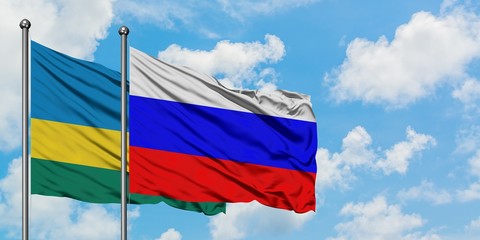 Rwanda and Russia flag waving in the wind against white cloudy blue sky together. Diplomacy...