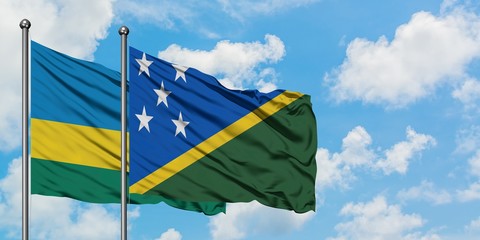 Rwanda and Solomon Islands flag waving in the wind against white cloudy blue sky together. Diplomacy concept, international relations.