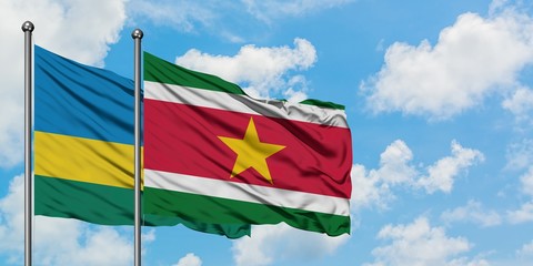 Rwanda and Suriname flag waving in the wind against white cloudy blue sky together. Diplomacy concept, international relations.