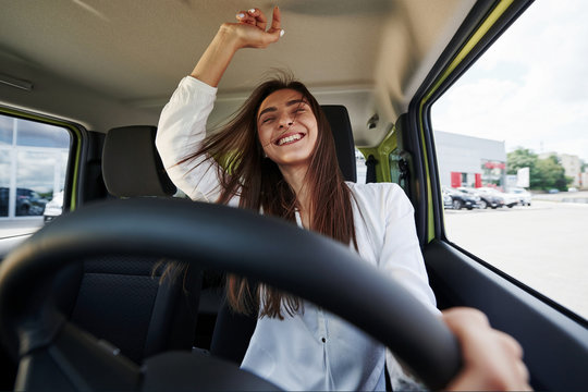 Happy Owner. Front View Of Woman That Drives Modern New Car In The City