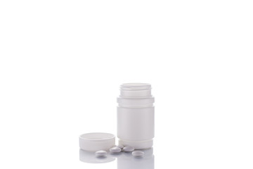 A vial of pills stands on a mirror surface on a white background in the center with a place for text..