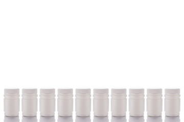Ten jars of pills and closed caps stand on a mirror surface on a white background in the middle.