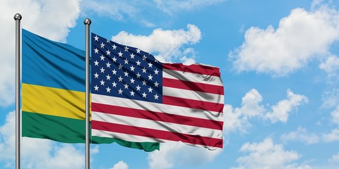 Rwanda and United States flag waving in the wind against white cloudy blue sky together. Diplomacy concept, international relations.