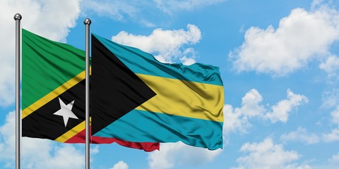 Saint Kitts And Nevis and Bahamas flag waving in the wind against white cloudy blue sky together. Diplomacy concept, international relations.