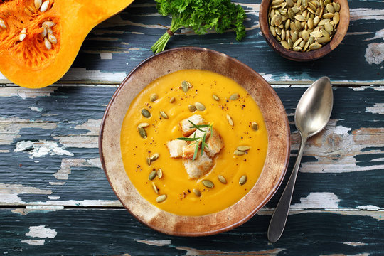 zuppa crema di zucca gialla su tavolo colorato verde rustico