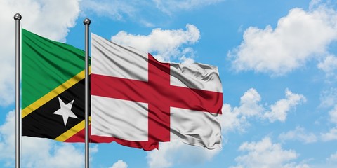 Saint Kitts And Nevis and England flag waving in the wind against white cloudy blue sky together....