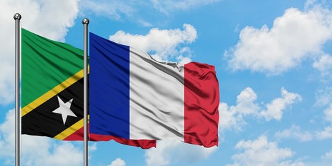 Saint Kitts And Nevis and France flag waving in the wind against white cloudy blue sky together....