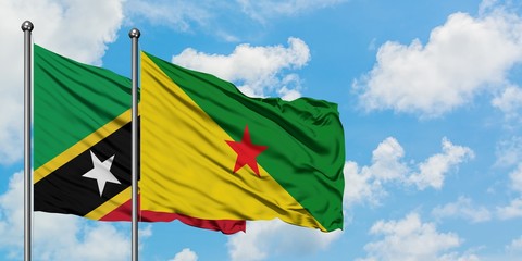 Saint Kitts And Nevis and French Guiana flag waving in the wind against white cloudy blue sky together. Diplomacy concept, international relations.