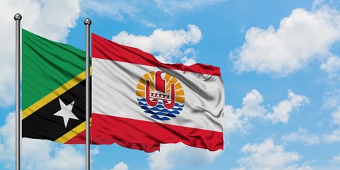 Saint Kitts And Nevis and French Polynesia flag waving in the wind against white cloudy blue sky...