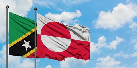 Saint Kitts And Nevis and Greenland flag waving in the wind against white cloudy blue sky together....