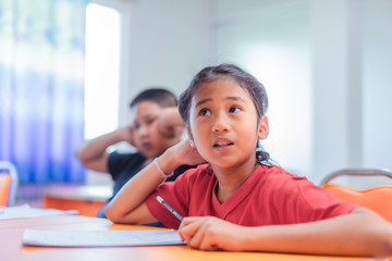 Asian elementary school children are studying in the classroom with an Asian female teacher.