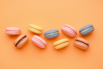 Different tasty macarons on color background