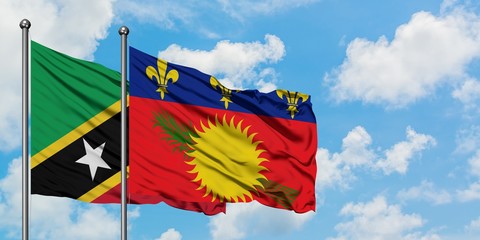 Saint Kitts And Nevis and Guadeloupe flag waving in the wind against white cloudy blue sky together. Diplomacy concept, international relations.