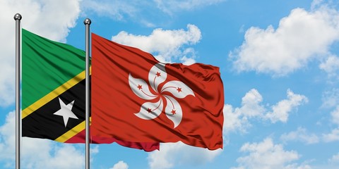 Saint Kitts And Nevis and Hong Kong flag waving in the wind against white cloudy blue sky together. Diplomacy concept, international relations.