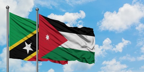 Saint Kitts And Nevis and Jordan flag waving in the wind against white cloudy blue sky together....
