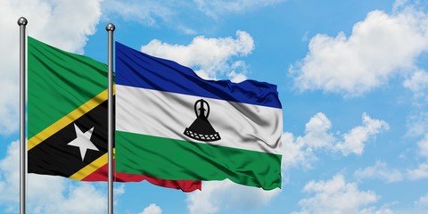 Saint Kitts And Nevis and Lesotho flag waving in the wind against white cloudy blue sky together....