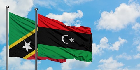 Saint Kitts And Nevis and Libya flag waving in the wind against white cloudy blue sky together....