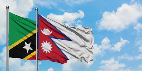 Saint Kitts And Nevis and Nepal flag waving in the wind against white cloudy blue sky together. Diplomacy concept, international relations.