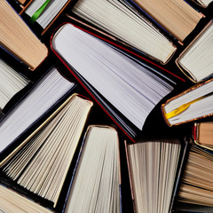 Lots of colourful thick open books stand on a dark background