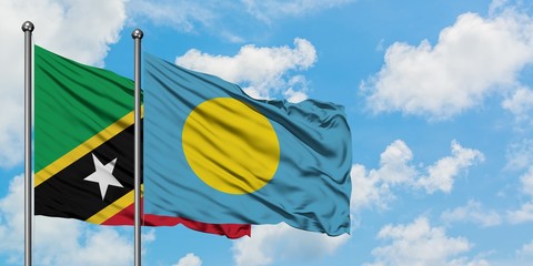 Saint Kitts And Nevis and Palau flag waving in the wind against white cloudy blue sky together. Diplomacy concept, international relations.