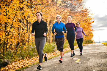 woman group out running together in an autumn park they run a race or train in a healthy outdoors...