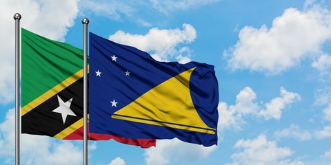 Saint Kitts And Nevis and Tokelau flag waving in the wind against white cloudy blue sky together. Diplomacy concept, international relations.