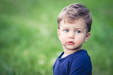 Cute little blond boy in blue t-shirt with beautiful blue eyes.