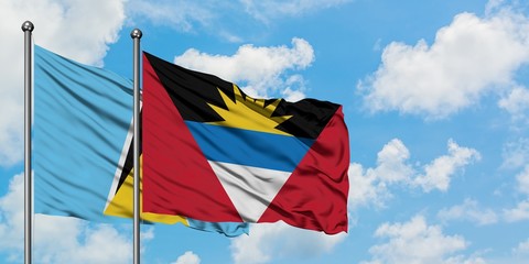 Saint Lucia and Antigua and Barbuda flag waving in the wind against white cloudy blue sky together....