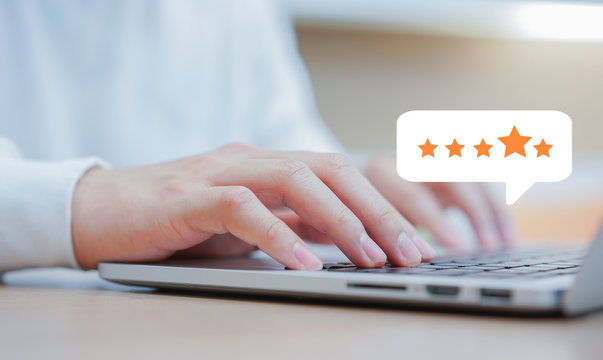 close up on customer man hand typing on keyboard laptop to giving good score point to review the service with star rating feedback icon level for satisfaction of business concept