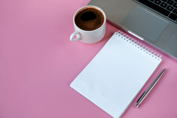 notebook, laptop, pen, black coffee Cup on pink background, copy space;