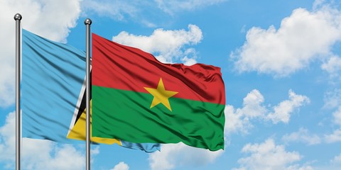 Saint Lucia and Burkina Faso flag waving in the wind against white cloudy blue sky together. Diplomacy concept, international relations.