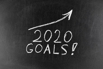 Year 2020 chalk text with a rising arrow on a blackboard. Chalkboard written with word 2020. New year success in business.
