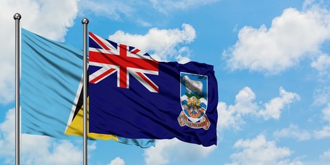Saint Lucia and Falkland Islands flag waving in the wind against white cloudy blue sky together....