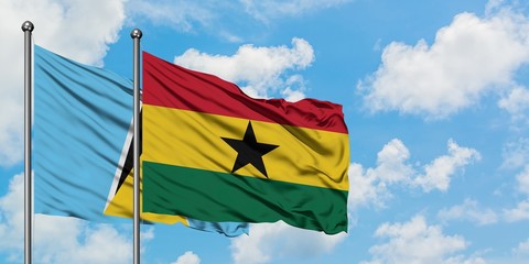 Saint Lucia and Ghana flag waving in the wind against white cloudy blue sky together. Diplomacy...