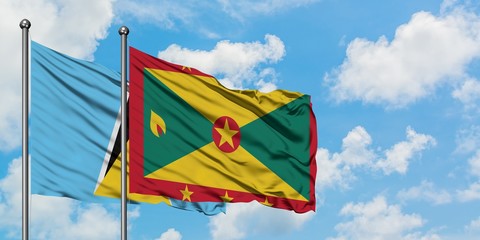 Saint Lucia and Grenada flag waving in the wind against white cloudy blue sky together. Diplomacy concept, international relations.