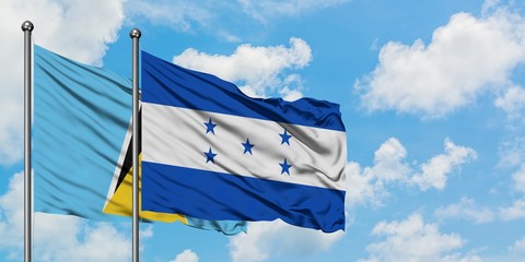 Saint Lucia and Honduras flag waving in the wind against white cloudy blue sky together. Diplomacy...