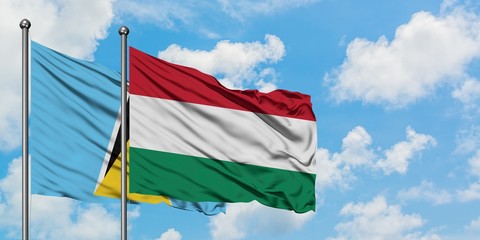 Saint Lucia and Hungary flag waving in the wind against white cloudy blue sky together. Diplomacy...