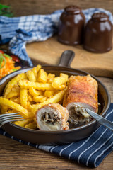 Fried chicken breast stuffed with mushrooms and cheese wrapped in ham served with fries and salad.