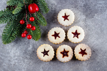 New Year 2020 Tree. Christmas Linzer cookies with jam and fir tree branch on gray concrete table background. Top view, flat lay