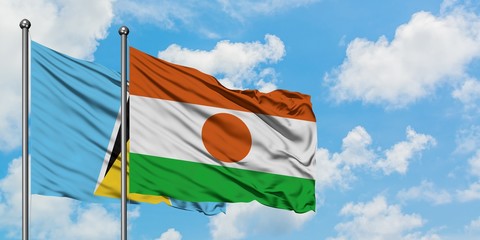 Saint Lucia and Niger flag waving in the wind against white cloudy blue sky together. Diplomacy...