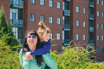 Mom hugs with her daughter on the background of a country house. A woman and a child are happy to...