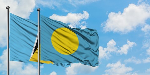 Saint Lucia and Palau flag waving in the wind against white cloudy blue sky together. Diplomacy concept, international relations.