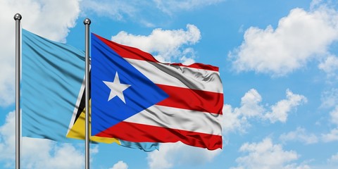 Saint Lucia and Puerto Rico flag waving in the wind against white cloudy blue sky together. Diplomacy concept, international relations.
