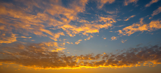 Panorama Sunlight with dramatic sky. Cumulus sunset clouds with sun setting down on dark background.Vivid orange cloud sky.