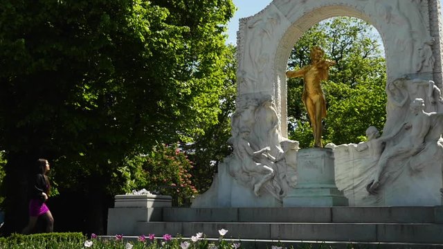 Woman Walks Stadpark, Stops and Looks at Johan Strauss Memorial - Slow Motion